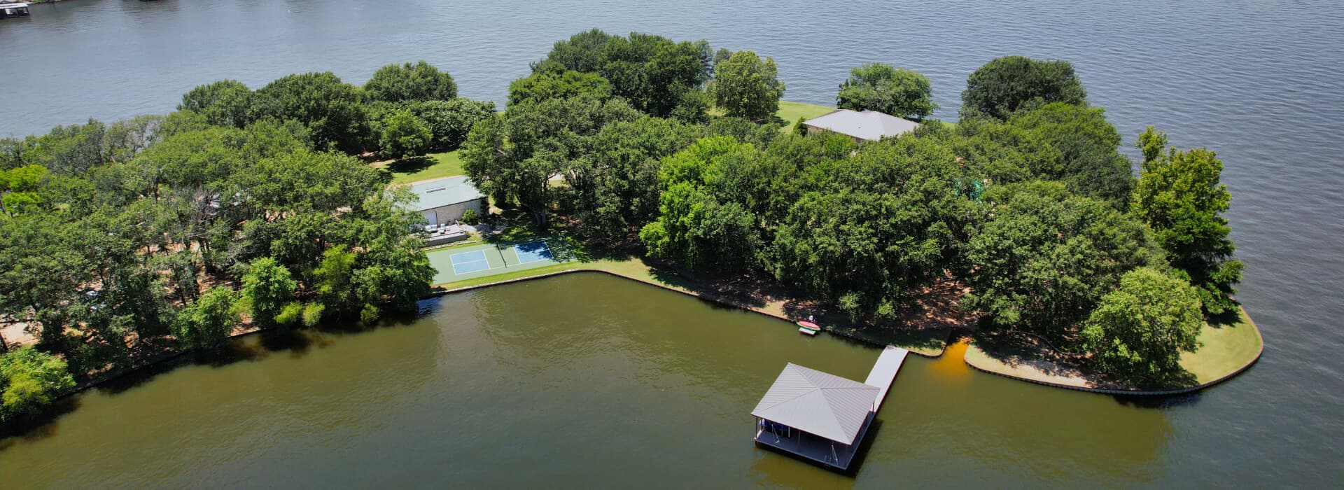 Aerial view of a lush green island with a dock, surrounded by water.