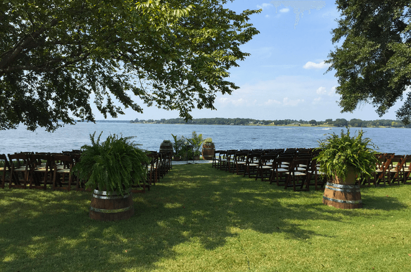 A scenic outdoor setting with chairs arranged for an event, overlooking a peaceful lake.
