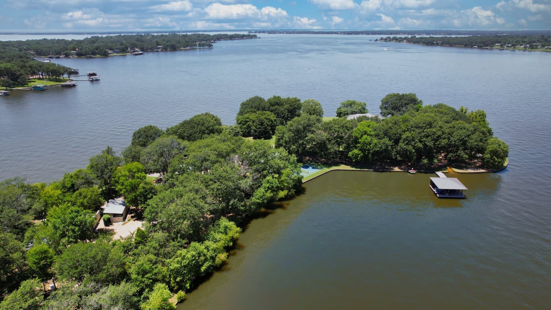 Aerial view of a lush green island surrounded by a wide river under a cloudy sky.
