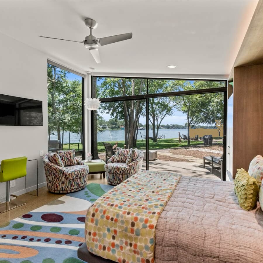 Bright and modern bedroom with a view of a lake framed by large windows.