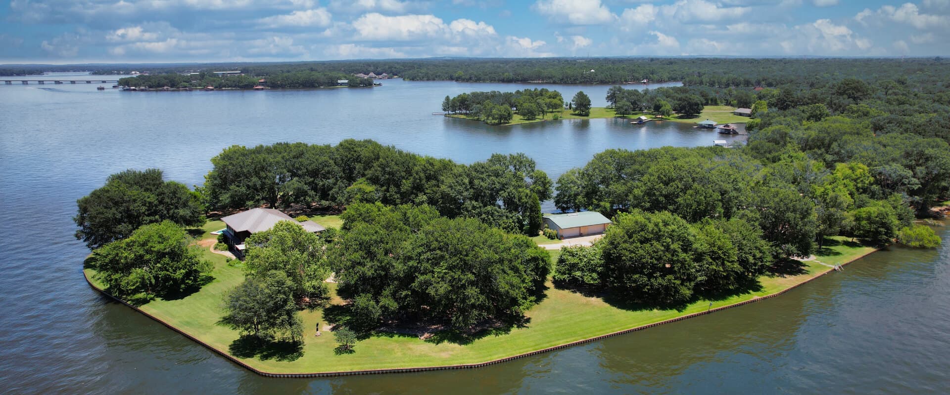 Aerial view of a lush, green island surrounded by a calm lake and blue sky.