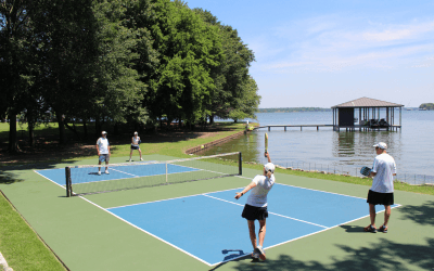 Four people playing pickleball on a sunny court by the lake.